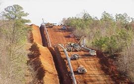 A group of trucks on the side of a dirt road.